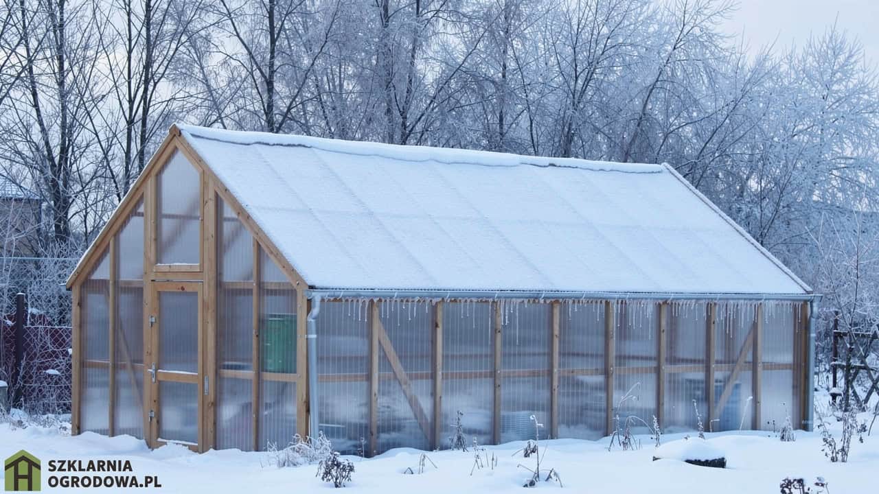 Drewniana szklarnia zimą pokryta śniegiem
